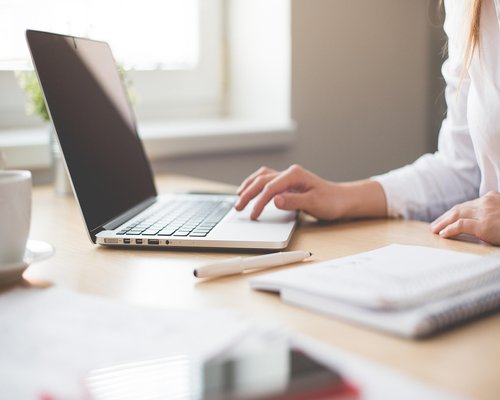 A professional typing on a modern responsive laptop setup near an office window