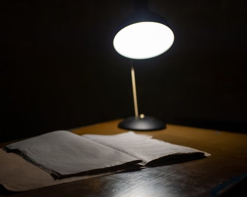 An adjustable table lamp providing soft warm light over an open physical notebook